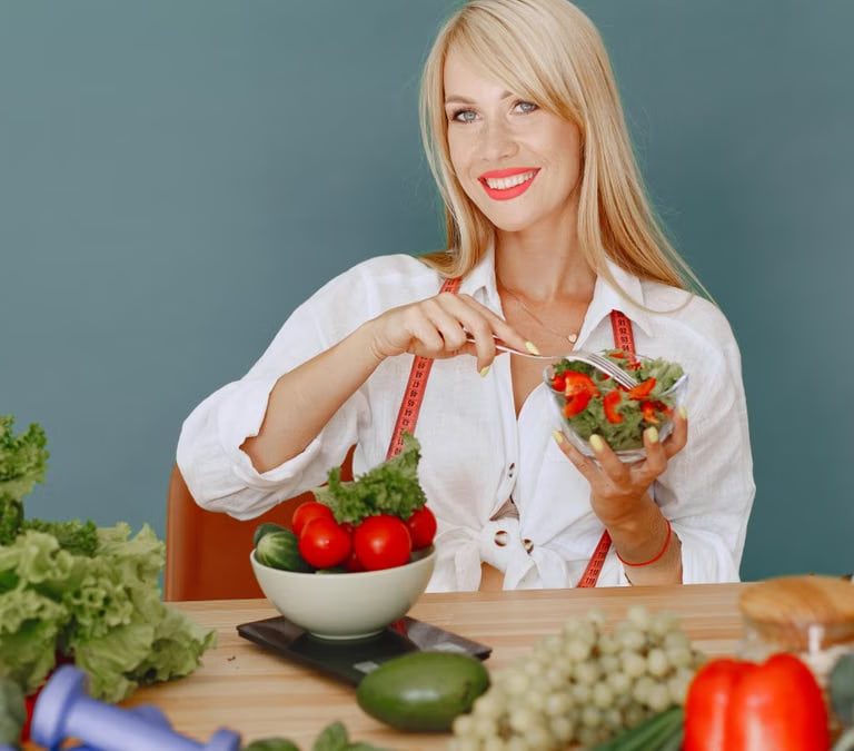 Blonde woman enjoying a fresh salad surrounded by vegetables, promoting healthy eating.